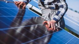 Man placing hands on solar panels on a rooftop