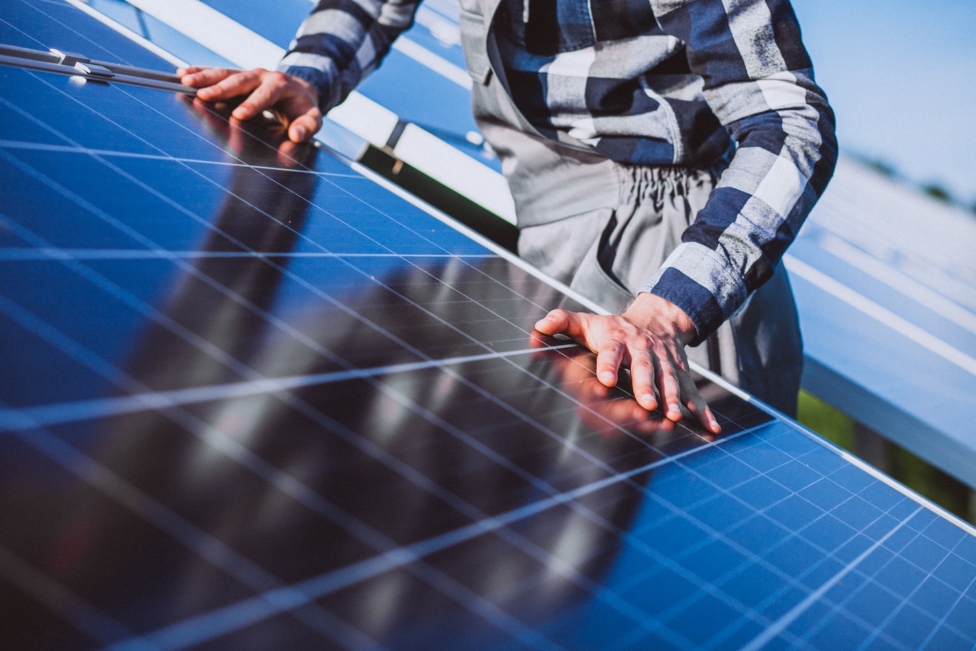 Man placing hands on solar panels on a rooftop