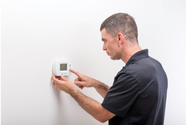 a man looking at a thermostat